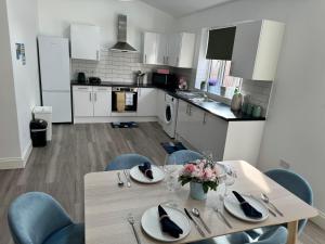 a kitchen with a table and chairs and a kitchen with white cabinets at Modern and Comfy 1-Bedroom Flat in Wembley in London