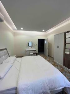 uma grande cama branca num quarto com uma janela em Liwan chalet - شاليه الليوان em Al Bukayriyah