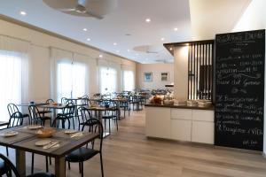 a restaurant with tables and chairs and a chalk board at Hotel Dafne in Punta Marina