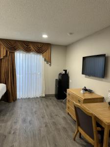 a hotel room with a bed and a desk and a television at Days Inn by Wyndham Medford in Medford