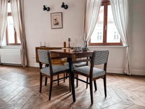 una mesa de comedor y sillas en una habitación con ventanas en Once Upon a Time in Cracow - Old Town Apartment en Cracovia