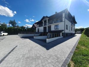 a large white house with a parking lot at JURA PARADISE in Olsztyn