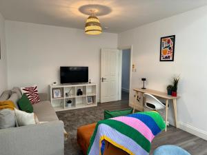 ein Wohnzimmer mit einem Sofa und einem TV in der Unterkunft Spacious 1-Bed Flat Near Wembley Stadium in London