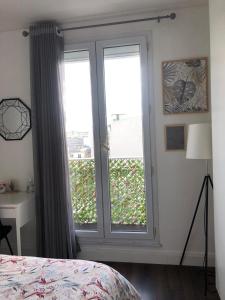 1 dormitorio con ventana grande con vistas a la ciudad en La veranda du parc, en Issy-les-Moulineaux