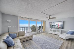 a living room with a couch and a balcony at Huge Beachfront Condo on Maderia Beach in St. Pete Beach
