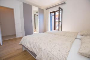 a white bedroom with a bed and a window at Apartments Marija in Funtana