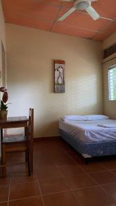 a bedroom with two beds and a table and a ceiling fan at Hostal Casa Bonita Ometepe in Rivas