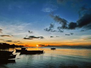 a group of boats on the water at sunset at Gloria's Beach House in Oslob