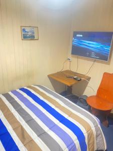 a bedroom with a bed and a flat screen tv at Hostal Papo in Osorno