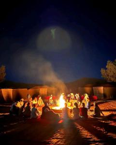 a group of people sitting around a fire at night at Overnight Desert Camp in Merzouga