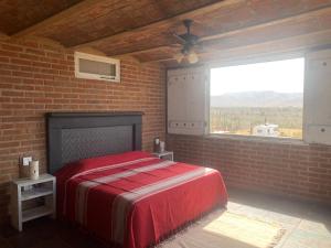 a bedroom with a red bed in a brick wall at Baja69 lodge in El Pescadero