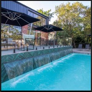 una piscina con agua azul y sombrillas en The Smart Home en Johannesburgo