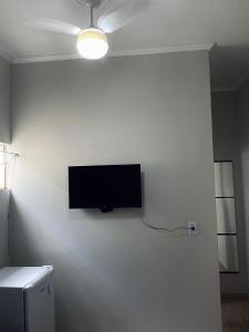 TV de pantalla plana colgada en una pared blanca en Quarto privativo no centro 02, en Itapira