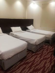 جوهرة الششة الجديدة1 في Al ‘Azīzīyah: ثلاثة أسرة في غرفة الفندق ذات شراشف بيضاء