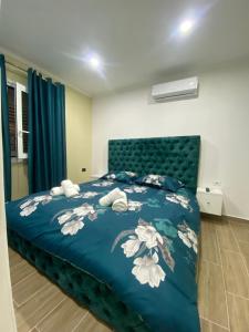 een slaapkamer met een blauw bed met witte bloemen erop bij Hodo guest house in Përmet