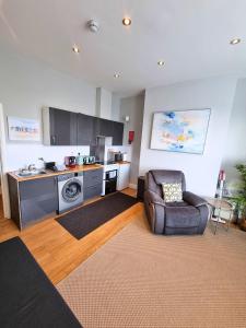 a kitchen with a couch and a chair in a living room at Portrush by the Sea - 1 West Beach in Portrush