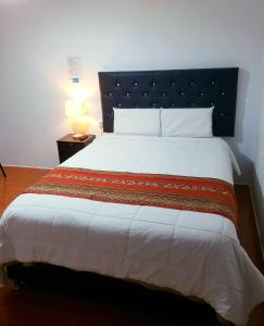 a bedroom with a large bed with a blue headboard at Cusco de mis Sueños Hostal - II in Cusco