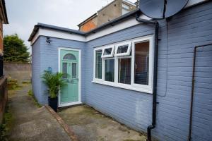 ein blaues Haus mit grüner Tür und Pflanze in der Unterkunft GOLDEN HAVEN in Reading