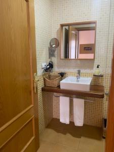 a bathroom with a sink and a mirror and towels at Apartamentos Caceres in Cáceres
