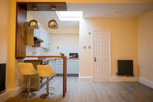 a kitchen with yellow walls and a counter and chairs at GOLDEN HAVEN- Central Reading Apartment in Reading
