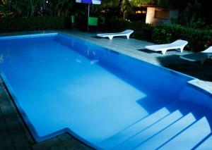 a swimming pool at night with two white chairs in it at Pousada do Peralta in Bonito