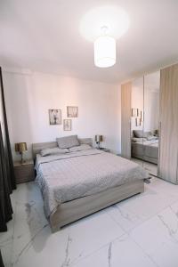 ein weißes Schlafzimmer mit einem großen Bett und einem Spiegel in der Unterkunft Bright 2 Bedroom flat in Sliema! in Sliema