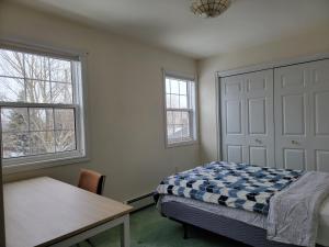 a bedroom with a bed and a table and two windows at Amy's house in Charlottetown