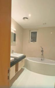 LUXURY 4 Bedroom Private Pool Villa at THE WAVE في مسقط: حمام به مغسلتين وحوض استحمام كبير