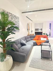 una sala de estar con un sofá gris y una palmera en LUXURY 4 Bedroom Private Pool Villa at THE WAVE en Mascate