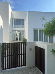 una casa blanca con una valla negra y ventanas en LUXURY 4 Bedroom Private Pool Villa at THE WAVE en Mascate