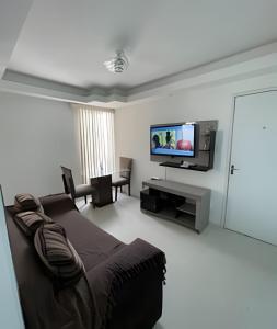 een woonkamer met een bed en een flatscreen-tv bij Aconchego Urbano: Espaçoso C/Ar in Feira de Santana