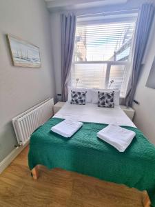 a bedroom with a large bed with green sheets and a window at Portrush by the Sea - 1 West Beach in Portrush