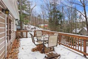 a balcony with a table and chairs in the snow at Chalet “Lendemain de ville” avec accès au lac in Saint Adolphe D'Howard