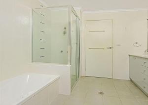 a white bathroom with a shower and a tub at Beach Road 9 The Sands in Batehaven
