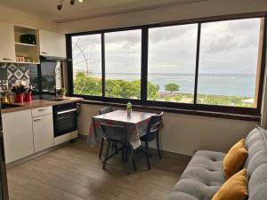 eine Küche mit einem Tisch und einem Sofa sowie einige Fenster in der Unterkunft Studio Teiki - calme, proche centre-ville, ferry & aéroport in Papeete
