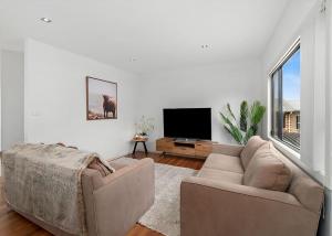 a living room with a couch and a flat screen tv at Golfers Dream managed by Batemans Bay Accom in Batemans Bay