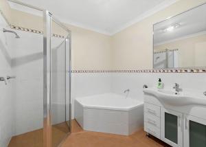 a white bathroom with a shower and a sink at Golfers Dream managed by Batemans Bay Accom in Batemans Bay +12 photos