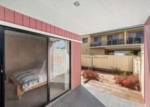 a sliding glass door of a building with a bed outside at Golfers Dream in Batemans Bay