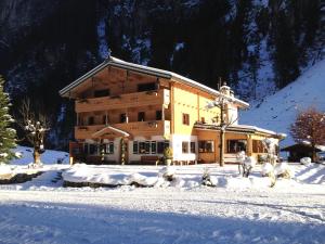 um grande edifício de madeira na neve com neve em Alpenhaus Lacknerbrunn em Mayrhofen