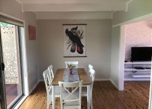 a dining room with a table and white chairs at Surf Beach Retreat in Surf Beach