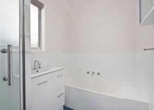 a white bathroom with a sink and a bath tub at Surf Beach Retreat in Surf Beach +7 photos