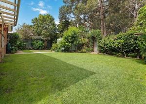 a yard with a large lawn with trees at Surf Beach Retreat in Surf Beach