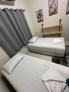2 Betten in einem Zimmer mit Vorhang in der Unterkunft Residencial Paraiso in Sinop