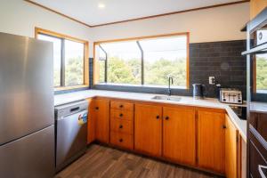 eine Küche mit Holzschränken und einem Kühlschrank aus Edelstahl in der Unterkunft Chapman House in Auckland