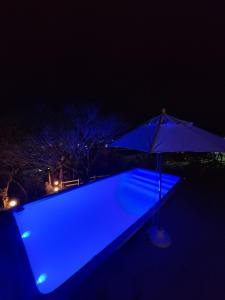 una piscina azul con sombrilla por la noche en Recanto da Vila - Chalé 01, en Governador Celso Ramos