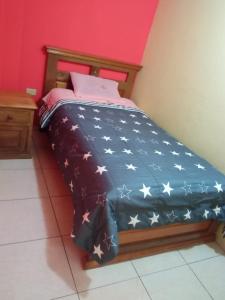 Una cama con una manta azul con estrellas. en HOSTAL EL CASTILLO SIGCHOS, en Sigchos