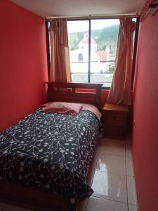 1 dormitorio con cama y ventana grande en HOSTAL EL CASTILLO SIGCHOS, en Sigchos