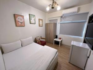 a small bedroom with a white bed and a window at Inn 逢甲Home in Taichung