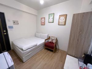 ein kleines Zimmer mit einem Bett und einem roten Stuhl in der Unterkunft Inn 逢甲Home in Taichung