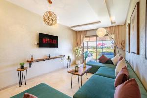 un salon avec un canapé bleu et une télévision dans l'établissement luxueux & spacieux appartement a prestigia, à Marrakech